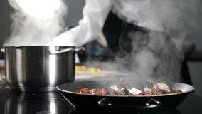 Cooking process. Boiling saucepan with white dense steam or vapor rising up. Female chef cooking in background. Blurred footage. Restaurant food concept. Seafood concept. 4 k video