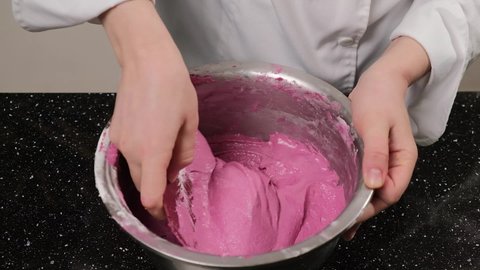 The pastry chef mixes the dough for the macarons in a stainless steel bowl.