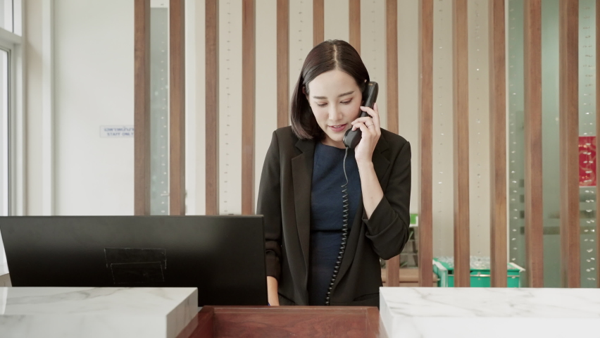 The hotel receptionist is talking on the phone with a customer to contact the hotel reservation