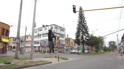 Bogota, Colombia; march 22 2021: Young man juggling and passing on a tightrope in the middle of a road with a red traffic light, as a circus show to beg money or coins to the drivers on the cars