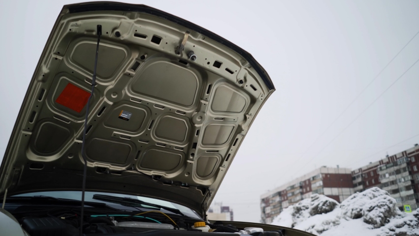 A car with an open hood is standing on the street.