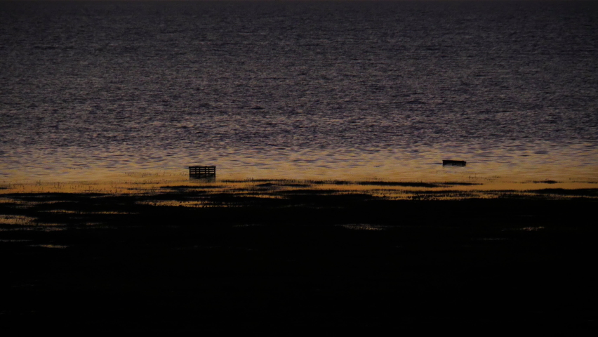 Two crab or lobster traps shown here sticking out of the water during low tide near the shoreline of Key West on a beautiful golden hour sunrise morning.