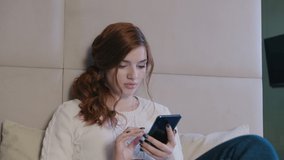 Beautiful Caucasian Woman In Beige Sweater Using Smartphone Or Cell Phone In Modern Room. Tapping, Scrolling, Watching Video, Content, Bloggs.