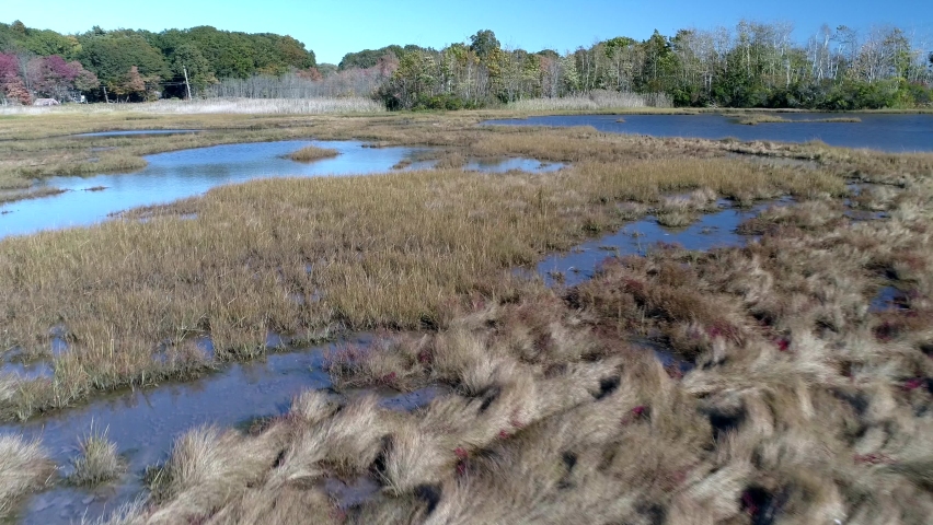 Aerial Drone - Fly Low Over Marsh Passing Over Swaths Of Water With Drone Shadow In View 4K