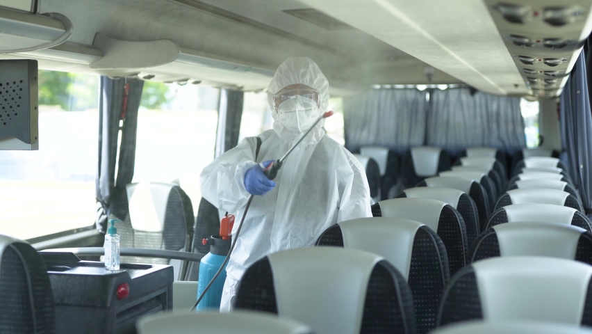 Sanitation worker in white protective suit cleaning the tram with ...