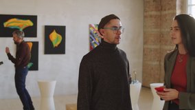 Young Caucasian man and woman discussing artwork on the wall while visiting exhibition in gallery - Powered by Shutterstock - Get 15% off with code: PIKWIZARD15