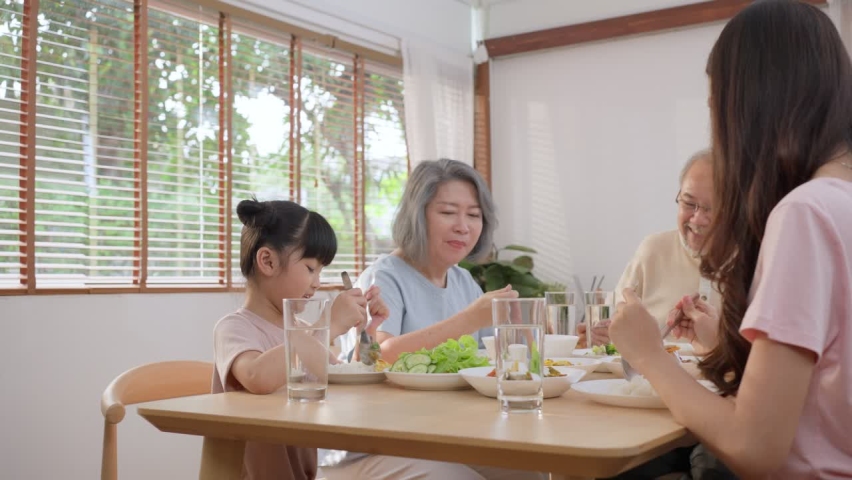 Big Asian happy family spend time having lunch on dinner table together. little kid daughter enjoy eating food with father, mother and grandparents. Multi-Generation relationship and activity in house Royalty-Free Stock Footage #1069519816