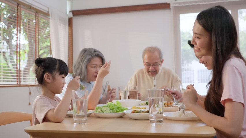 Big Asian happy family spend time having lunch on dinner table together. little kid daughter enjoy eating food with father, mother and grandparents. Multi-Generation relationship and activity in house Royalty-Free Stock Footage #1069519816