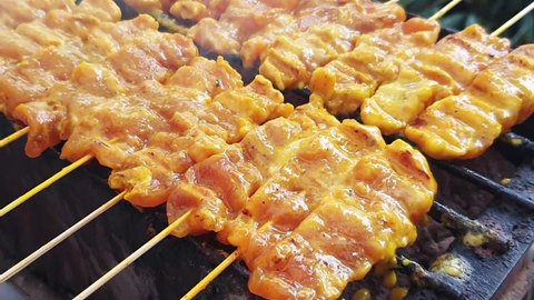 Pork satay grilled by charcoal grill.Street food of thailand.Pork thai barbecue is delicious,Hand held shot.
