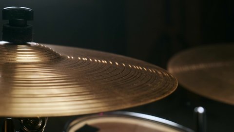 Musician hits the percussion cymbal. Rocker creates music in a dark studio.