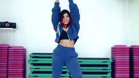 Girl dancer with red hair in a tracksuit performs modern dance in the studio.