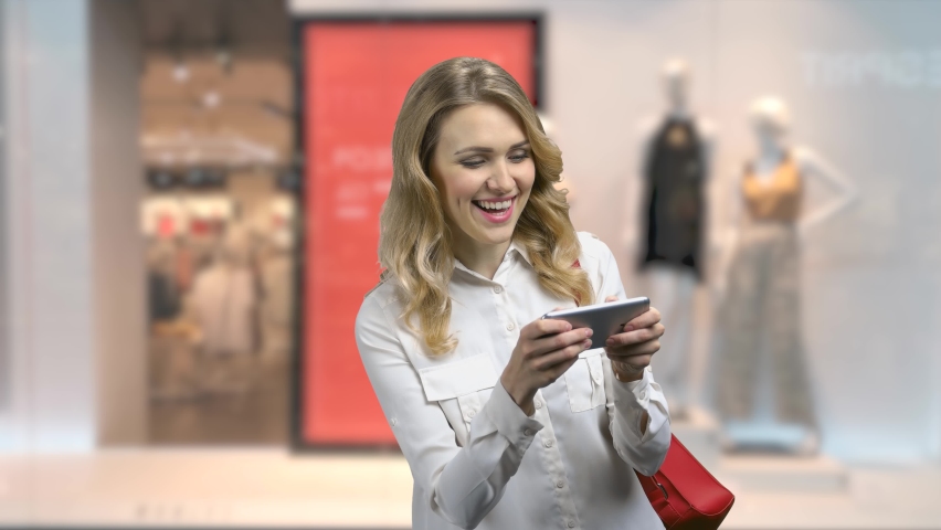 Young expressive woman plays game on her smartphone.