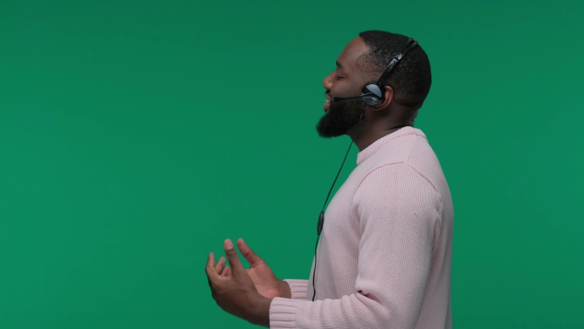 Smiling african american man wearing wireless headset talking to microphone isolated on Green Screen, Chroma Key, customer service agent Royalty-Free Stock Footage #1069543111