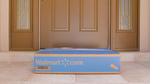 NORTH PORT, FLORIDA - MARCH 24, 2021: Man retrieving Walmart box delivered to residential doorstep. Walmart+ offers free package home delivery to it's members.