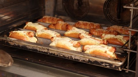 Sausage in the dough in the oven. fast food baking process in a small bakery. ungraded video