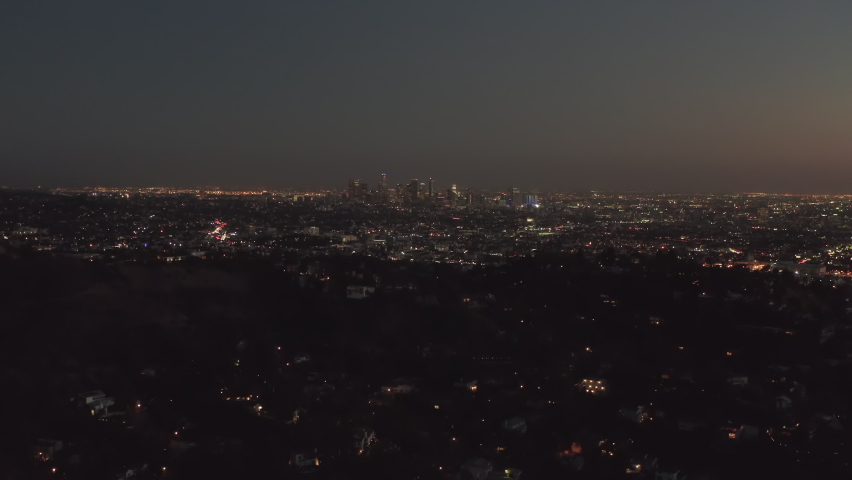 AERIAL: Over Hollywood Hills at Night with view on Downtown Los Angeles view