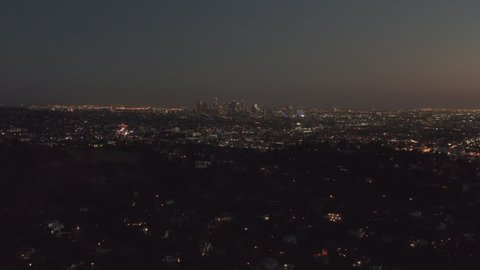 AERIAL: Over Hollywood Hills at Night with view on Downtown Los Angeles view
