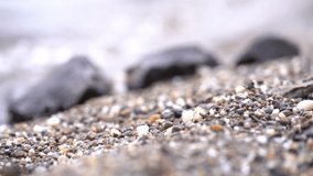 Extremely slow motion pull focus between from a rocky beach to rocks on the beach