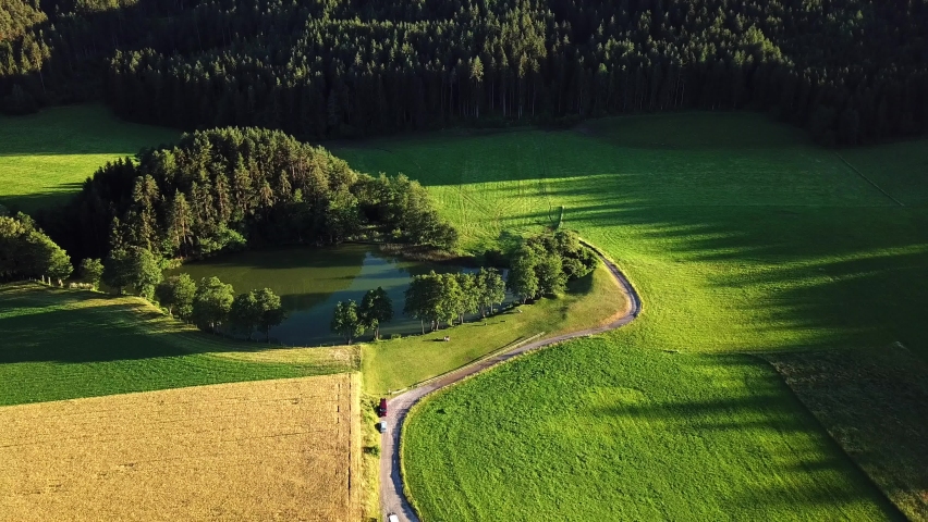 Aerial view of a hidden pond surrounded by trees on an Austrian mountain valley