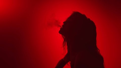 Sensual passion woman smoking with blowing smoke at night party red studio background slow motion. Relaxed sexy lady dancing with fume performing modern choreography. Shot with RED camera in 4K