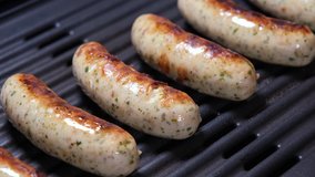 Removing sausages from the grill close up. 4K resolution video. Delicious Fried Roasting Grilled Meat Dish Ready For Picnic or Party. Cooking Fast Food Take Away Sausages Meal.