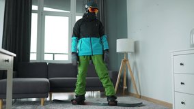 Fun video. Man dressed as a snowboarder depicts snowboarding on a carpet in a cozy room. Waiting for a snowy winter