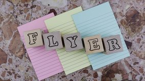 Flyer concept with alphabet letters on wooden blocks or cubes placed over three colored sheets of notepaper on a marbled stone background. Flat lay. Rotating table - Powered by Shutterstock - Get 15% off with code: PIKWIZARD15