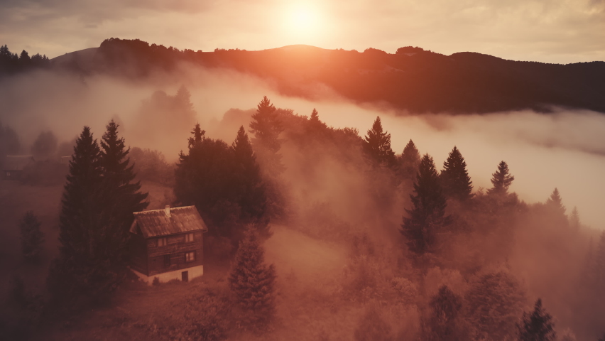 Horror fog sunset on mountain aerial. Red mist over spooky pine forest. Nobody sun nature landscape. Foggy clouds at scary wild coniferous trees. Cottage at fir wood in bloody shadows. Cinematic shot Royalty-Free Stock Footage #1069575964