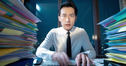 Time-lapse photography close up of asian young businessman is overtime working with documents in office