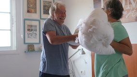 couple of two happy seniors having fun playing together on the bed at home fighting with pillows enjoying - pillows war indoors in the morning
 - Powered by Shutterstock - Get 15% off with code: PIKWIZARD15