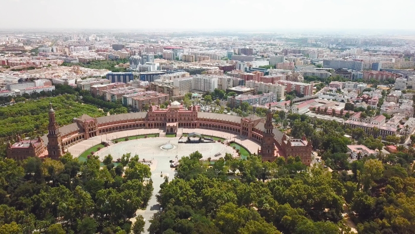 Generic cinematic aerial view of beautiful city of Seville , capital of Andalusia Province in south of Spain, Costa del Sol. Beautiful Espana Square in the centre of Seville. Drone going backward
