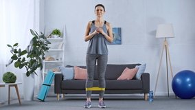 Sportswoman training legs with resistance band in living room
