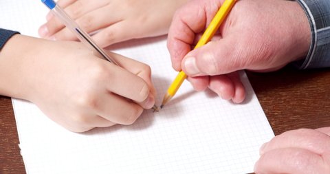 Close-up of children and elderly hands drawing tic-tac-toe on paper. Home leisure.