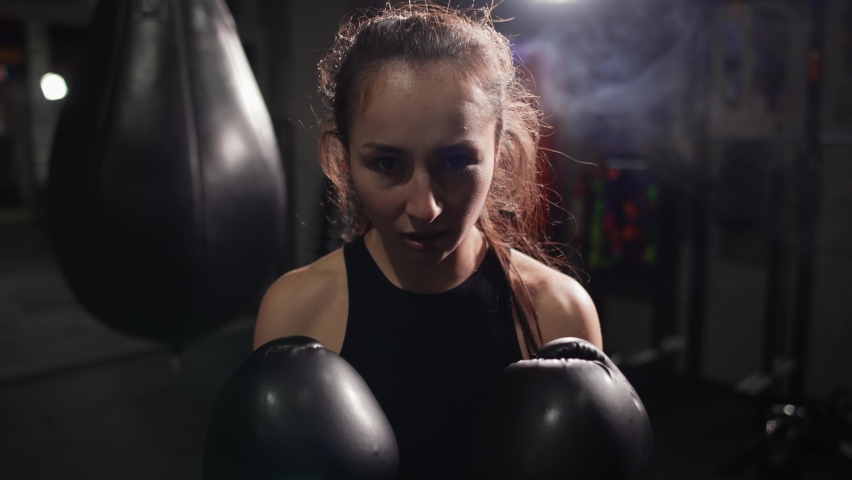 Female boxer standing at dark gym, looking intensely at the camera and screaming Royalty-Free Stock Footage #1069602784