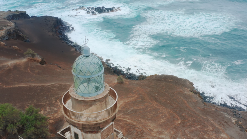Drone flying over Volcano Interpretation Center of Capelinhos located on Faial Island, Azores, Portugal, Europe. Man walking on road at lighthouse washing by atlantic ocean waves, 4k footage