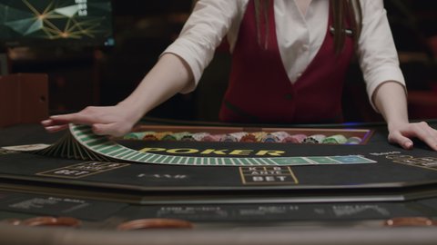 Croupier behind gambling table in a casino. Dealer shuffles the cards. Nightlife