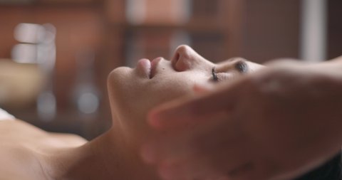Young attractive cute brunette woman gets face massage in spa salon. Healthy lifestyle and body care concept. Slow motion, close-up