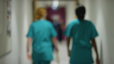 Blurred Medical Staff Walking Away  In Hospital Corridor