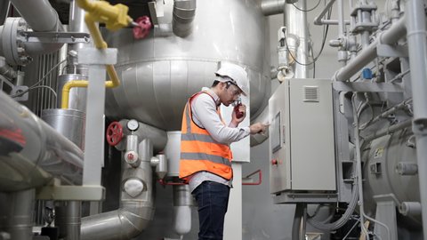 Industrial Worker working with confident in modern industry generator Power plant and motor manufacturing industry. Engineer is controlling the large generator in power plant, Cold control machinery.