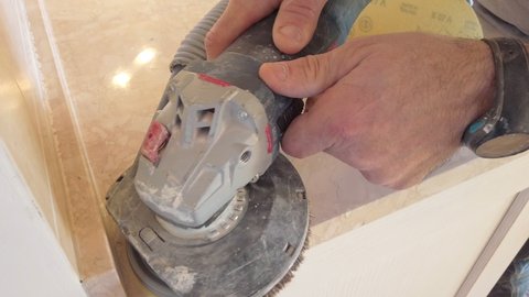 close up of worker hand with pad sander tool sanding a kitchen top of marble.