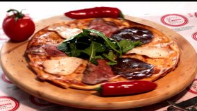 4K video shot conceptual pizza shot of Italian Pizza with mixed carpaccio and ham turning over wooden board with presentation on wooden board buying now.
