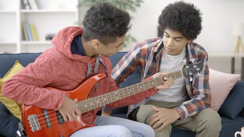 Teen friends learning to play electric guitar together, common interests, hobby