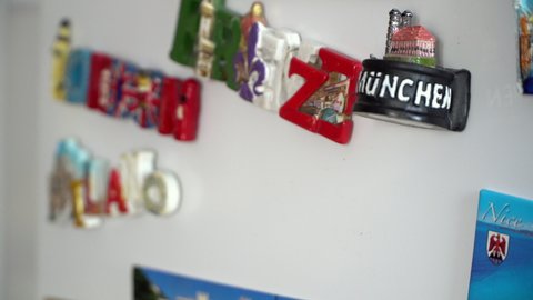 Adding a new fridge magnets from the last vacation, travel concept, cinematic dof