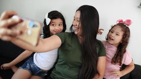 Family speaking on video call using cellphone. Asian mother with little girls daughters speaking long distance communication