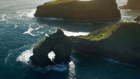 Flores Island, Azores, Portugal. A rock with an arque between giant cliffs and the wild Atlantic. Picturesque sunrise during low tide. High quality 4k footage.