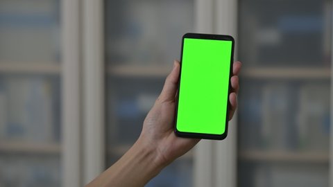 Hand held smartphone: man using phone with green and blue mock-up screen chroma key and scrolling and tapping the screen