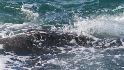 Sea blue wave crashes against stone. Troubled sea