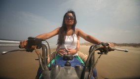 video footage of a woman on a Quad, driving at a beach