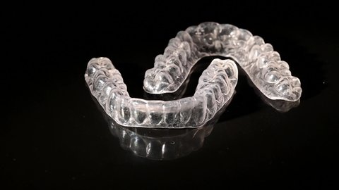 Transparent removable braces swirls around on a black background