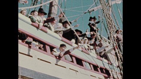 1970s: People dressed as pilgrim on tall ship at sea, pointing to land. People debark tall ship to small boat alongside. Boat lands on shore. People cut and stack wood on ground.